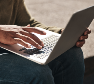 Close-up of a person typing on a laptop outdoors