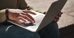 Close-up of a person typing on a laptop outdoors