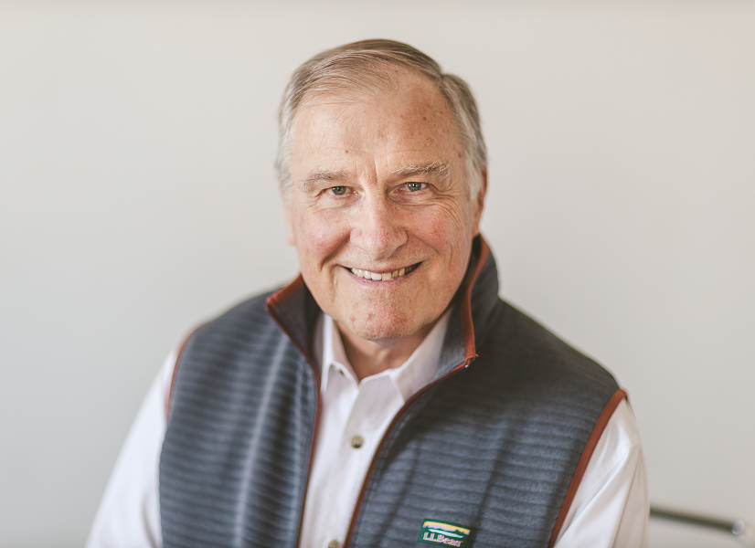 Professional headshot of an man smiling in a grey vest and white collared shirt.