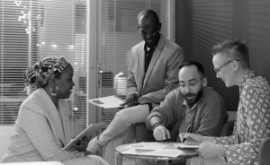 Four coworkers reviewing paperwork and taking notes during a group chat.