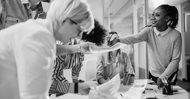 Woman passing a printed paper to a coworker.